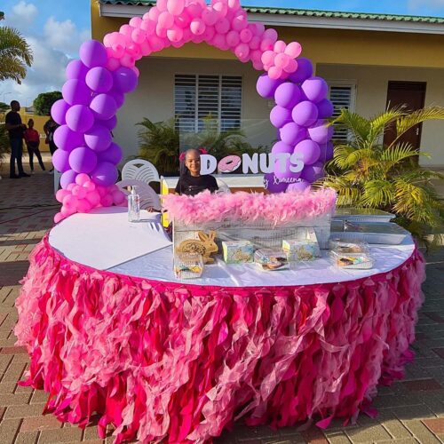 a table with colorful table dressing and a balloon arch behind it