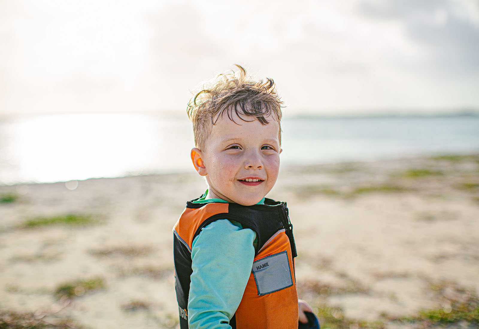 Young kid in a lifejacket smiling at the camera