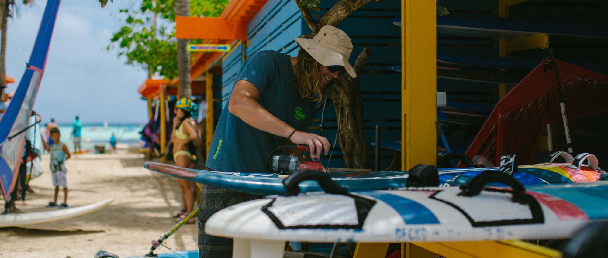 Man sanding surfboard in beach hut