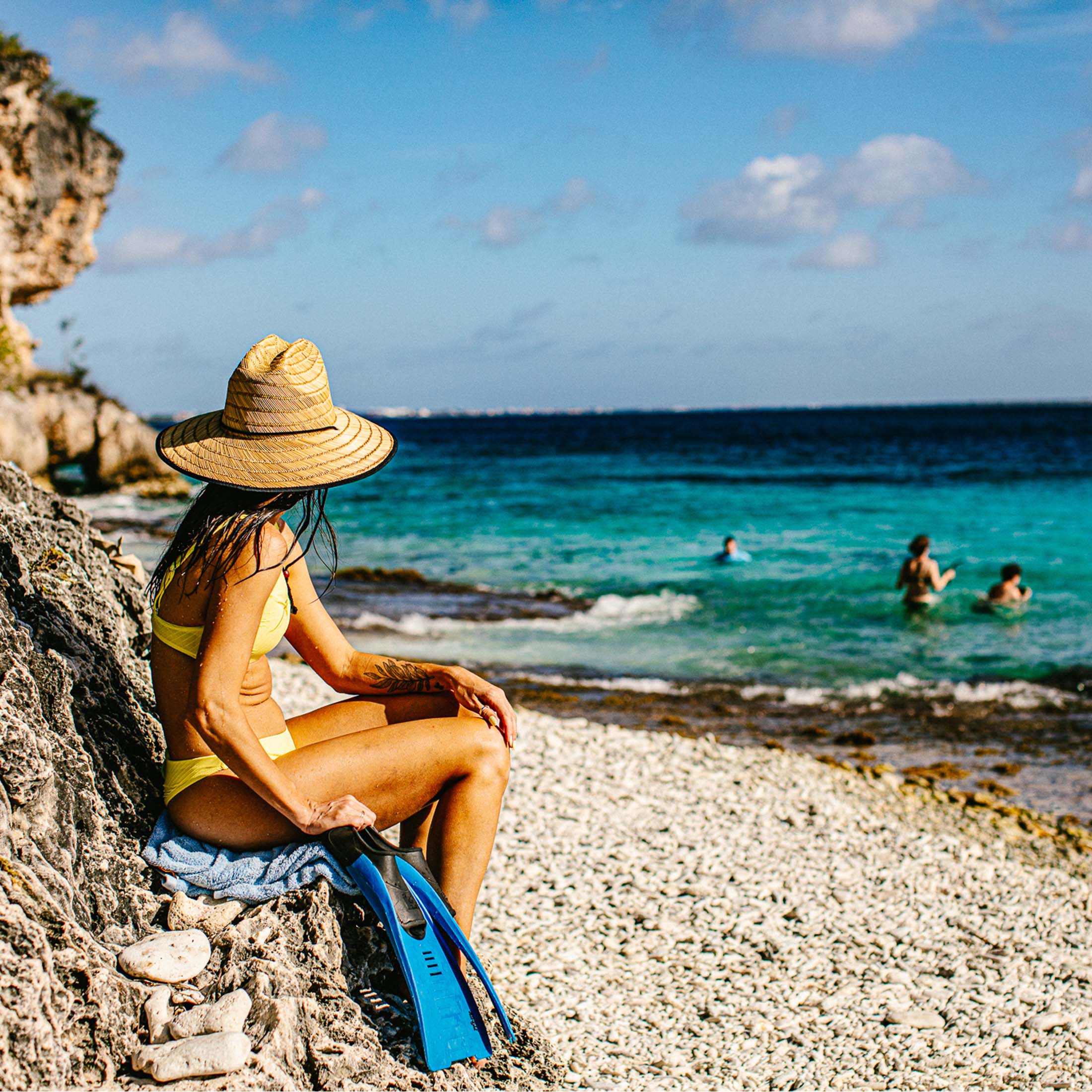 Vrouw zittend op een rots kijkend naar de oceaan