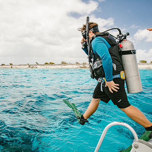 Man jumping into the water wearing scuba diving gear
