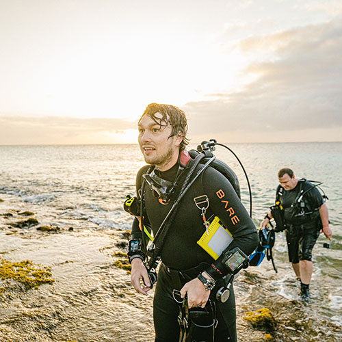 Two men coming out of the water in scuba gear
