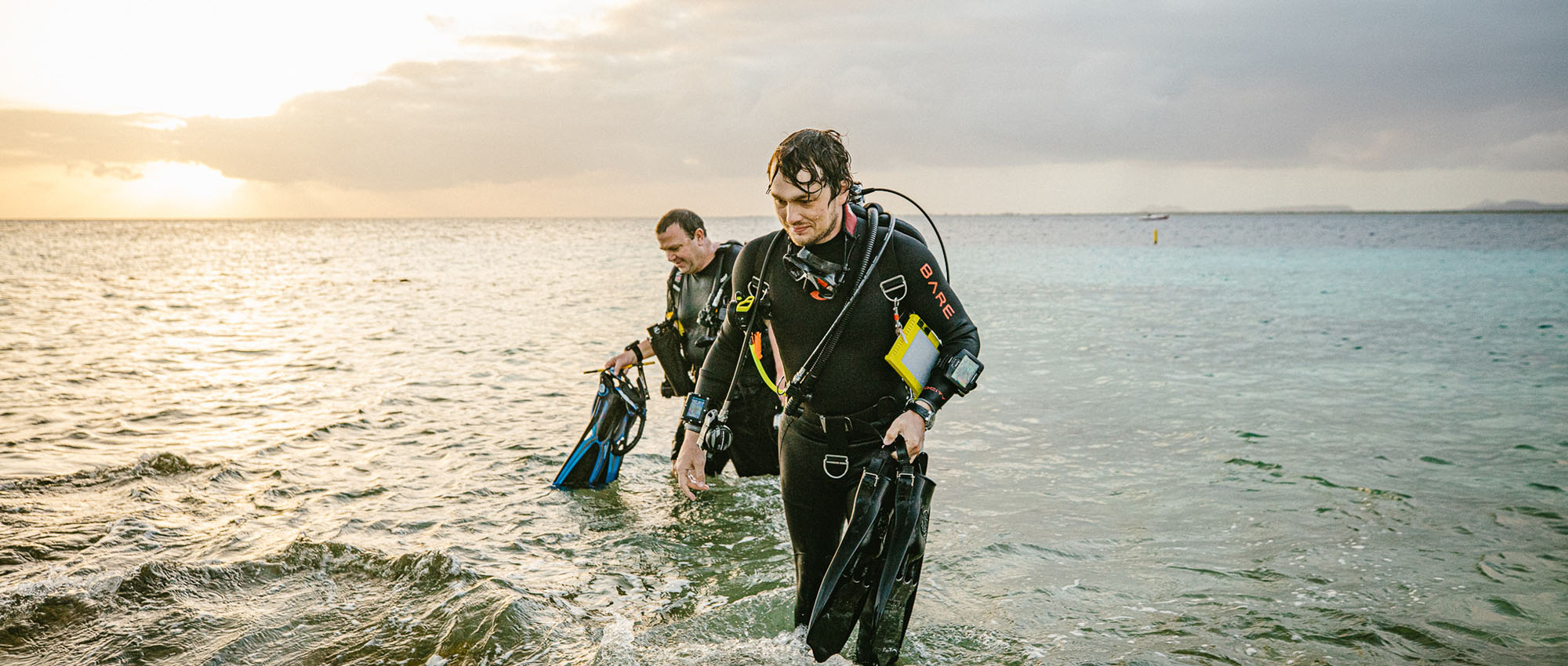 Two men in scuba gear getting out of the water