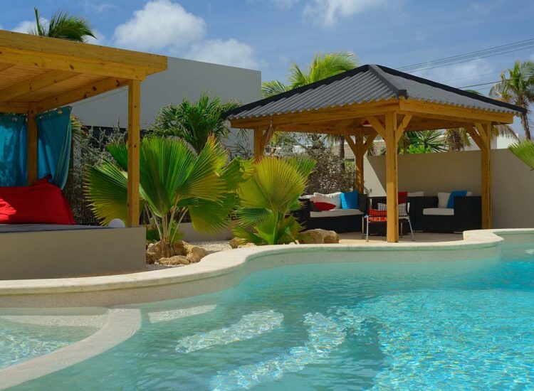 Outdoor pool area with wooden cabanas