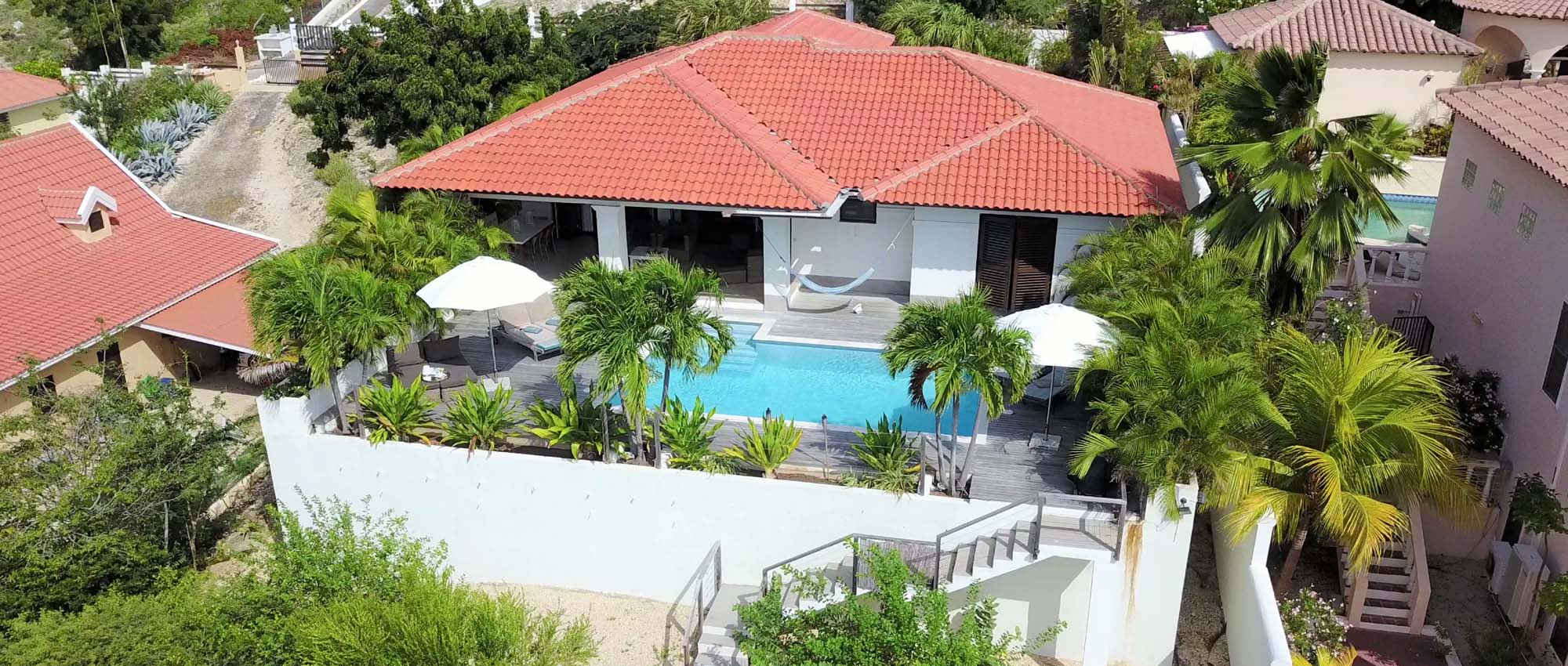 Luchtfoto van zwembad in achtertuin omgeven door palmbomen