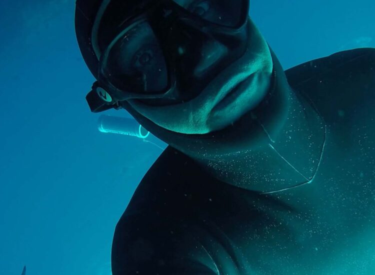 Close up shot of diver with a shark in the background
