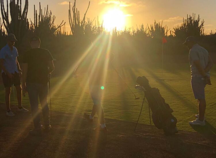 Groep mensen op een golfbaan tijdens zonsondergang