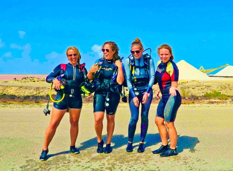 Four women standing next to each other wearing scuba gear