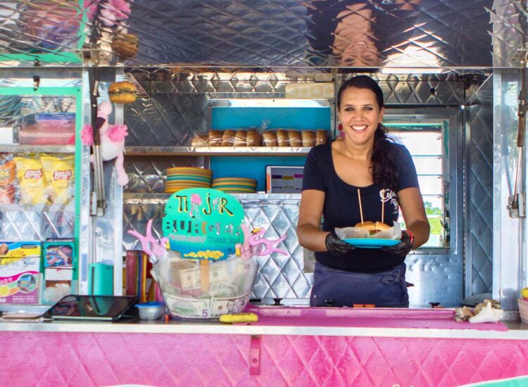 Woman holding a plate with a burger inside a food truck