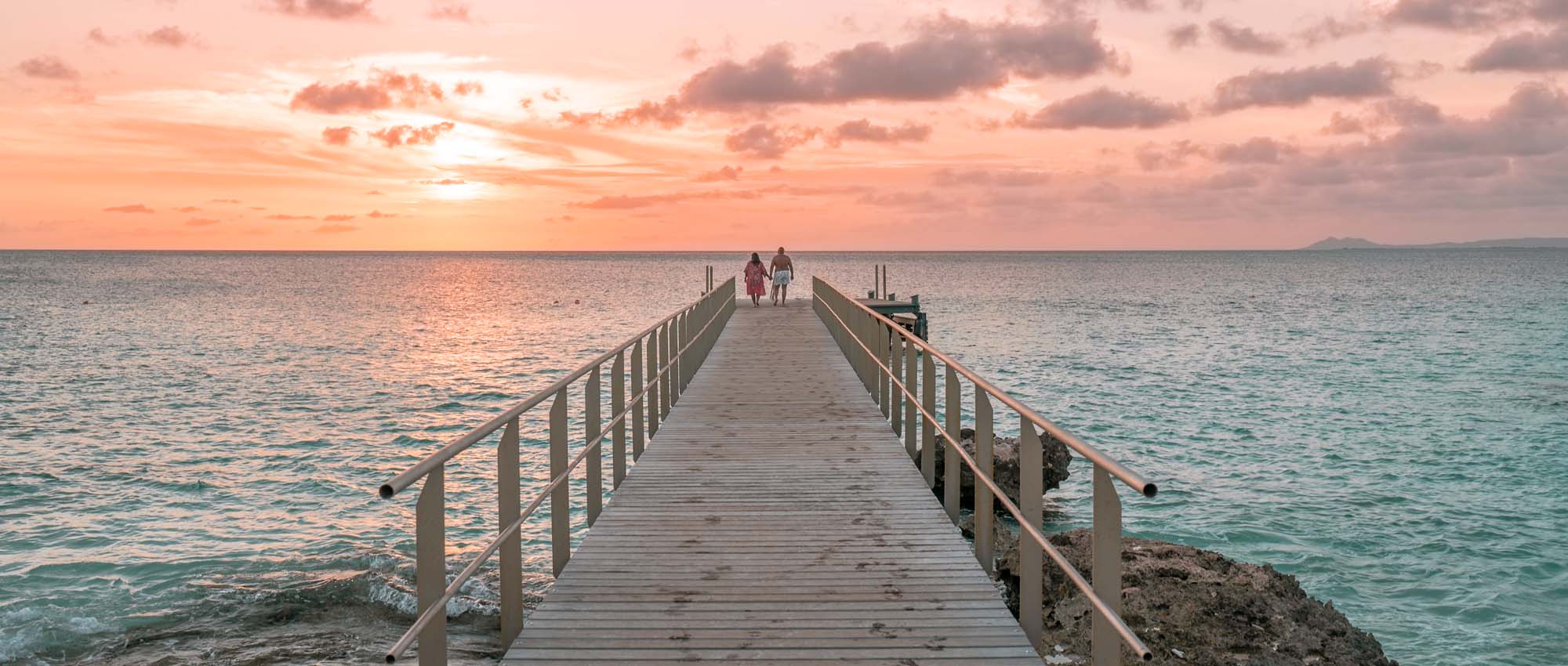 Couple walking on pier into the distance