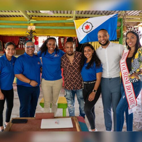 Groepsfoto van artiest Ir Sais en Tourism Corporation Bonaire team glimlachend naar de camera