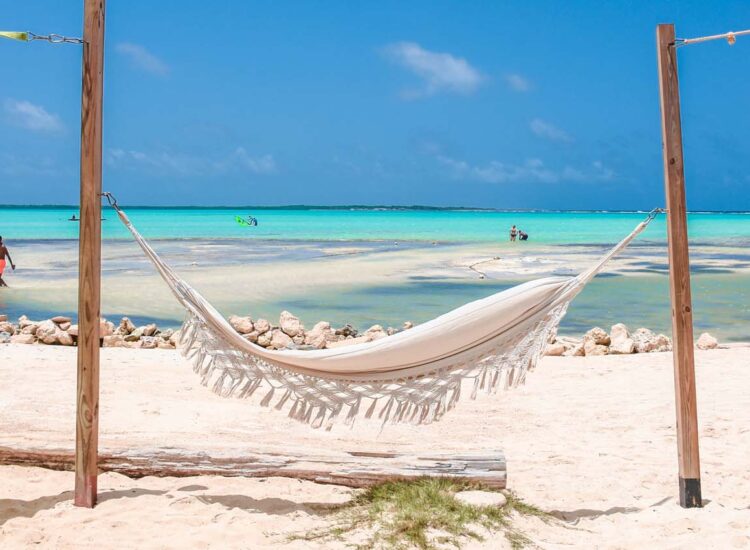 White hammock attached to two poles on the beach