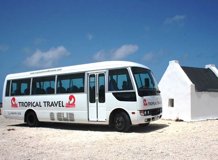 White bus parked next to a white hut by the ocean