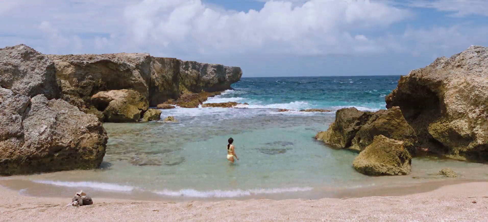 Women standing in ocean water surrounded by beach rocks