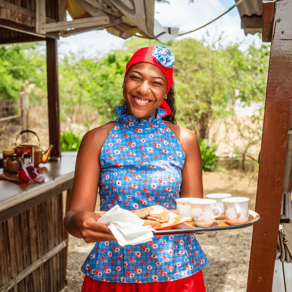 Woman holding platter of tea cups and smiling at camera