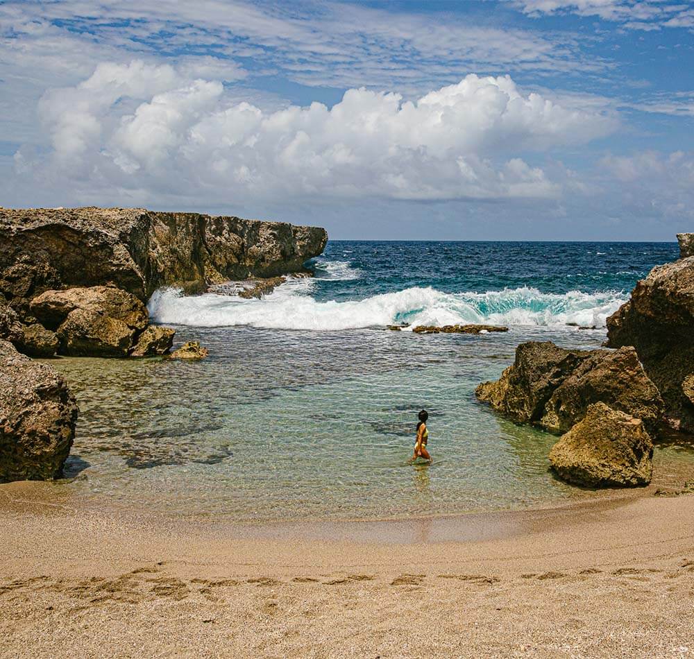 Women standing in ocean water surrounded by beach rocks